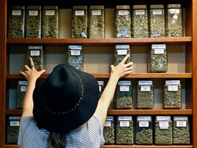 Assistant manager Jaclyn Stafford arranges glass display containers of marijuana on shelves at The Station, a retail and medical cannabis dispensary, in Boulder, Colo.