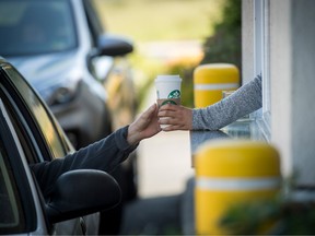 An employee passes a drink order to a customer at the drive-thru of a Starbucks Corp. coffee shop in Rodeo, California.