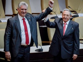 Outgoing Cuban President Raul Castro (R) raises the arm of Cuba's new President Miguel Diaz-Canel after he was formally named by the National Assembly, in Havana on April 19, 2018.