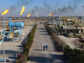 FILE - in this Thursday, Jan. 12, 2017 laborers walk down a path in the Nihran Bin Omar field north of Basra, Iraq. Emerging from a grueling war with the Islamic State group for more than three years, Iraq plans to open more of its untapped oil and gas resources to foreign developers to boost reserves and to increase sorely needed revenues for post-war construction by offering rights to explore and develop hydrocarbon-rich areas.