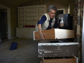 In this Wednesday, April 11, 2018, photo, mudslide survivor Mari Mitchel moves drawers covered in mud in her bedroom, in Montecito, Calif. The mudslide carried away everything from massive pieces of antique family furniture to a tiny pouch filled with her most treasured jewelry, including her wedding and engagement rings.
