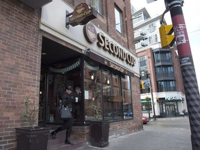 A customer carries her coffee as she leave a Second Cup coffee retailer in Toronto on Monday Dec. 5, 2016. Second Cup looking to convert some of its coffee shops into recreational cannabis dispensaries and lounges.