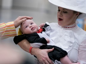 Mindy Groves, of Germantown, Md., dressed as Mary Poppins, holds her daughter Elizabeth, dressed as a penguin, as they wait in line for Awesome Con, at the Walter E. Washington Convention Center in Washington, Friday, March 30, 2018. Awesome Con is a sci-fi, comics, and gaming festival in "celebration of geek culture" with comics, movies, television, toys, and games.