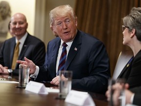 Gov. Pete Ricketts, R-Neb., left, listens as President Donald Trump speaks to Sen. Joni Ernst, R-Iowa, during a meeting with governors and lawmakers in the Cabinet Room of the White House, Thursday, April 12, 2018, in Washington.