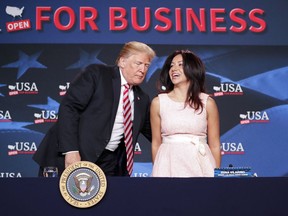 President Donald Trump, left, holds the chair for Irina Vilarino, right, owner, Las Vegas Cuban Cuisine, as they take their seats at an event to promote Trump's tax cut package at Bucky Dent Park in Hialeah, Fla., Monday, April 16, 2018.
