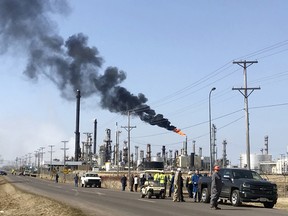 This photo provided by KQDS_FOX21 in Duluth, Minn., shows vehicles and personnel outside the Husky Energy oil refinery Thursday morning, April 26, 2018, after a tank containing crude oil or asphalt exploded at the large refinery in Superior, Wis. Authorities say several people were injured. The flame at the right is a normal part of refinery operations.
