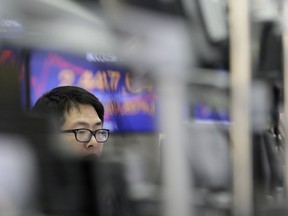 A currency trader watches the computer monitors near the screens showing the Korea Composite Stock Price Index (KOSPI) at the foreign exchange dealing room in Seoul, South Korea, Friday, April 13, 2018. Asian stock markets were mostly higher Friday following overnight gains on Wall Street. Risk sentiment returned as the U.S. explores the possibility of returning to trade talks with 11 countries and clarifies that it is consulting allies before making a final decision on possible military strikes against Syria.