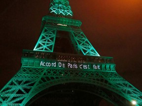 FILE - In this file photo dated Friday Nov.4, 2016, the Eiffel Tower lit up in green to mark the success of the Paris Agreement to slash man-made emissions of carbon dioxide and other global warming gases to counter climate change, in Paris. Inscription reads, "it's done". Diplomats and environmentalists are gathering in Bonn, Germany, for two-weeks of talks to keep working on the rules governing the Paris climate accord.