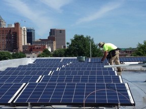 In this June 3, 2015 photo made available by NC WARN, workers install a solar power system on the roof of Faith Community Church in Greensboro, N.C.. The installation and the electricity the panels generated prompted a dispute being considered by the North Carolina Supreme Court that will be heard on Tuesday, April 17, 2018. State utilities regulators have ruled the group that funded the $20,000 cost of the solar panels violated state law protecting regulated monopoly electric utilities was illegally producing electricity "for the public." The group, NC WARN, says it was an allowable private power agreement with the church alone.