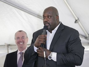 New Jersey Governor Phil Murphy, left, watches as Newark-native Shaquille O'Neal speaks during an event in Newark, N.J., Tuesday, April 10, 2018. Politicians and other guests were participating in a symbolic "topping-off" ceremony for a 23-story building in downtown Newark.