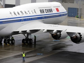 FILE- In this Sept. 29, 2014, file photo, a worker walks next to first Boeing 747-8 Intercontinental airplane to be delivered to Air China in Everett, Wash., before a delivery ceremony. In their escalating conflict over trade, what the U.S. and China are leaving off their tariff lists tells as much as what's on the lists. China put smaller planes on its list, but excluded the 747 and other big planes made in the U.S. by Boeing Co.