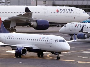 FILE- In this Jan. 8, 2018, file photo a Delta Connection Embraer 175 aircraft, foreground, taxis to a gate at Logan International Airport in Boston. Delta Air Lines, Inc. reports earnings Thursday, April 12, 2018.