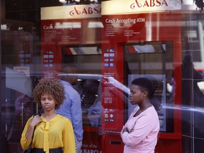 FILE- In this March 1, 2016, file photo, two women stand outside a building used by South Africa's ABSA bank in Cape Town, South Africa. Roughly seven out of every 10 adults worldwide now has some form of a bank account, the World Bank said Thursday, April 19, fueled largely by the proliferation of cell phone-based bank accounts and other simple bank account programs in places like India and Sub-Saharan Africa.