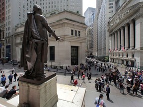 FILE- In this May 24, 2016, file photo, the statue of George Washington, on the steps of the Federal Hall National Monument, overlooks Wall Street and the New York Stock Exchange, right, in New York's Financial District. The U.S. stock market opens at 9:30 a.m. EDT on Thursday, April 5, 2018. .