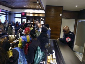 A plain-clothed police officer, right, mans a position behind the counter at the Starbucks that has become the center of protests Monday, April 16, 2018, in Philadelphia. The CEO of Starbucks arrived in Philadelphia hoping to meet with two black men who were arrested when the coffee chain's employees called 911 and said they were trespassing. Meanwhile, protesters took over the shop Monday.