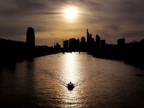 A man steers his motor boat on the river Main with the banking district in background as the sun sets in Frankfurt, Germany, Tuesday, April 24, 2018.