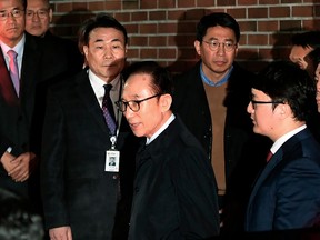FILE - In this March 23, 2018, file photo, former South Korean President Lee Myung-bak, center, gets into a car as he is transferred to a detention center, at his residence in Seoul, South Korea. South Korean prosecutors say on Monday, April 9, 2018, they've indicted Lee over bribery, embezzlement and other charges.