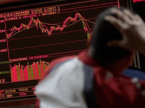 A man looks at an electronic board displaying stock trading index at a brokerage house in Beijing.