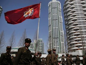 FILE - In this April 13, 2017, file photo, North Korean soldiers carry the Korean People's Army flag as they walk past residential buildings along Ryomyong street, in Pyongyang, North Korea. North Korea is racing forward with major development projects some experts believe are aimed at expanding a market for rented or privately owned real estate to bolster his regime against the bite of sanctions.