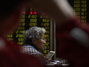 In this April 3, 2018 photo, a woman chats with her friends as they monitor stock prices at a brokerage house in Beijing. Shares were higher in Hong Kong and South Korea on Monday, April 30, 2018,  following the release of reassuring manufacturing data for China, though many Asian markets are closed for holidays.