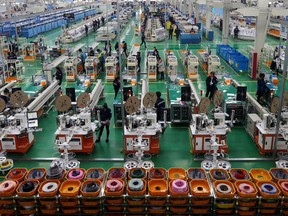 FILE - In this Oct. 20, 2017 photo, workers assemble automobiles' accessories in a factory in Huaibei in central China's Anhui province. A monthly survey has found that China's factory activity slipped by a fraction on slightly softer demand. The official purchasing managers' index released on Monday, April 30, 2018,  came in at 51.4 for April, easing from 51.5 in the previous month. (Chinatopix via AP, File)
