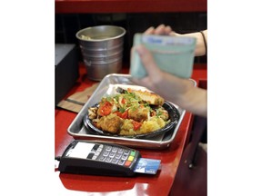 In this Tuesday, April 10, 2018, photo, a customers uses a credit card machine to pay for food at Peli Peli Kitchen in Houston. Owner Thomas Nguyen had a change of heart after transitioning one of his three Peli Peli South African fine dining restaurants and his Peli Peli Kitchen fast casual location to a no-cash policy.