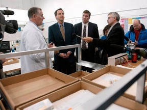 FILE - In this Nov. 12, 2003, file photo, CanadaDrugs.com Director of Pharmacy Robert Fraser, left, takes Minnesota Gov. Tim Pawlenty, second left, on a tour of the Internet pharmacy CanadaDrugs.com in Winnipeg, Manitoba in Canada. The Canadian online pharmacy is expected to be fined $34 million for importing counterfeit cancer drugs and other unapproved pharmaceuticals into the United States. Canada Drugs, which calls itself that nation's largest internet drugstore, and its founder, Kris Thorkelson, not seen, are being sentenced Friday, April 13, 2018, after pleading guilty to felony charges in the U.S. state of Montana.