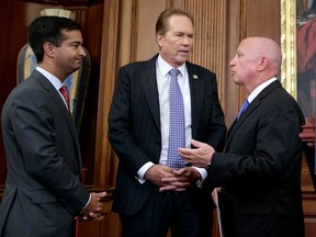 FILE - In this Sept. 27, 2017, file photo, from left, Rep. Carlos Curbelo, R-Fla., Rep. Vern Buchanan, R-Fla., and House Ways and Means Committee Chairman Kevin Brady, R-Texas, confer before a news conference at the Capitol in Washington. Already one of the wealthiest lawmakers on Capitol Hill, Buchanan could become even wealthier after he and other Republicans muscled a sweeping rewrite of the U.S. tax code through Congress that has breaks for the industries that generate most of his income. The tax code overhaul signed into law late last year by President Donald Trump is especially generous to real estate businesses and car dealerships _ the main sources of Buchanan's income.