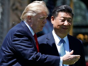 FILE - In this April 7, 2017, file photo, U.S. President Donald Trump gestures as he and Chinese President Xi Jinping walk after their meetings at Mar-a-Lago in Palm Beach, Fla. A year after Trump tried to disarm Xi at Mar-a-Lago with smooth talk and hospitality, he's resorted to hard ball and found that Xi is willing to throw it back. But at least for now, the acrimony over trade is unlikely to spill over into sensitive national security issues.