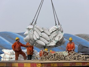 In this March 22, 2018, photo, workers load imported soybeans at a port in Nantong in east China's Jiangsu province. China on Wednesday, April 4, 2018 vowed to take measures of the "same strength" in response to a proposed U.S. tariff hike on $50 billion worth of Chinese goods in a spiraling dispute over technology policy that has fueled fears it might set back a global economic recovery. The Commerce Ministry said it would immediately challenge the U.S. move in the World Trade Organization. (Chinatopix via AP)