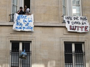 Students pull a supply bag from the windows next to banners reading "Against the Immigration law project, One more school in the struggle" at a blocked entry of the Institute of Political Studies(IEP) or Sciences Po, in Paris, France, Wednesday, April 18, 2018. French students intensified blockades of universities over the government's reform.