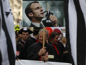 Lawyers and magistrates hold a placard with a portrait of French President Emmanuel Macron during a demonstration as part of a nation wide day of protest against a government draft law on Justice, in Paris, Wednesday April 11, 2018.