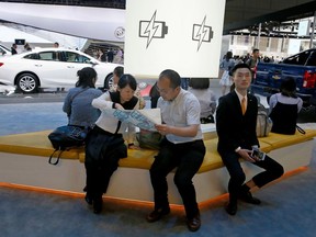 FILE - In this April 19, 2017, file photo, visitors to the stands of GM brands Chevrolet and Buick seat near a section promoting electric power during Auto Shanghai 2017 show at the National Exhibition and Convention Center in Shanghai, China. China has announced plans to allow full foreign ownership of automakers in five years, ending restrictions that have strained relations with Washington and other trading partners.