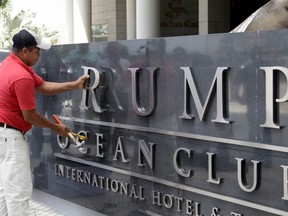 FILE - In this March 5, 2018 file photo, a man removes the word Trump, off a marquee outside the Trump Ocean Club International Hotel and Tower in Panama City, Panama. The Britton & Iglesias firm, which has represented the Trump Organization in its fight to continue running the hotel, addressed a letter dated March 22 to President Juan Carlos Varela that appealed for help days before an emergency arbitrator declined to reinstate the Trump management team to a luxury waterfront hotel.
