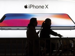 FILE - In this Monday, Nov. 6, 2017, file photo, residents pass by an advertisement for the iPhone X in Beijing, China. Apple shares have been falling in early 2018 on fears that the iPhone X has not been a hit with customers. (AP Photo/Ng Han Guan, File) ORG XMIT: NYBZ130