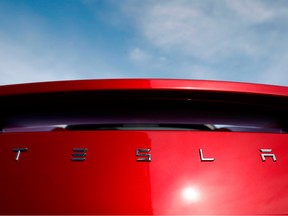 The sun shines off the rear deck of a roadster on a Tesla dealer's lot.