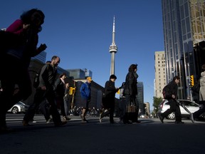 Pedestrians pass in front of the CN Tower in Toronto, Ontario.