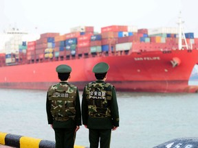 Chinese police officers watch a cargo ship at a port in Qingdao in China's eastern Shandong province on March 8, 2018.