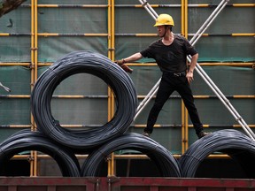 A worker moving reels of steel cable at a construction site in China.