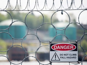 Oil tanks are seen behind razor wire topping a floating chain link fence surrounding the Kinder Morgan marine terminal in Burrard Inlet just outside of metro Vancouver, B.C.