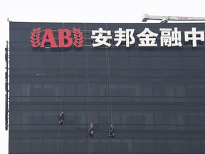 Workers clean windows on the Anbang Insurance building in Beijing on May 10, 2018. A Chinese court jailed Wu Xiaohui, the former high-flying head of troubled Anbang Insurance Group for 18 years, for defrauding the company of more than US$10 billion.