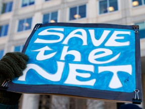 A woman holds a 'Save the Net' protest sign during a demonstration against the repeal of net neutrality outside the Federal Communications Commission headquarters in Washington, D.C. on December 13, 2017.