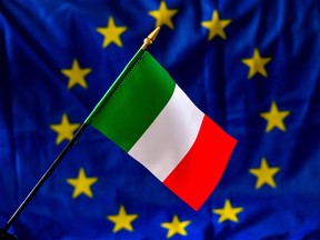 A picture taken on May 30, 2018 shows an Italian flag in front of the European Union flag. Italy, one of the European Union's biggest economies, has been plunged into crisis after President Sergio Mattarella at the weekend vetoed the new government's nomination of a fierce euro skeptic as economy minister.