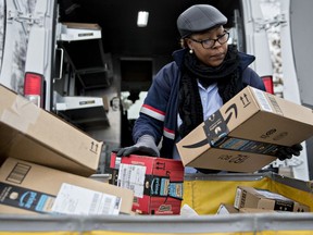 A letter carrier holds Amazon.com Inc. packages while preparing a vehicle for deliveries at the United States Postal Service Joseph Curseen Jr. and Thomas Morris Jr. processing and distribution centre in Washington.