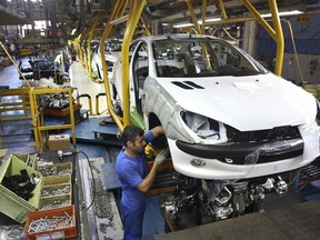 FILE - In this Oct. 11, 2014 file photo, an Iranian worker assembles a Peugeot 206 at the state-run Iran-Khodro automobile manufacturing plant near Tehran, Iran. From brand-new airplanes to oilfields, billions of dollars of deals stand on the line for international corporations as President Donald Trump weighs whether to pull America out of Iran's nuclear deal with world powers.