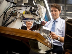 Prime Minister Justin Trudeau and Ontario Premier Kathleen Wynne try their hand at stitching leather, at the Toyota announcement Friday.