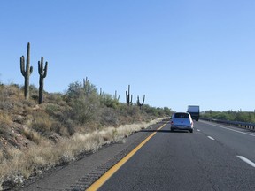 In this June 21, 2013, photo, traffic moves past several saguaro cactuses along the northbound lanes of the Interstate 17 in New River, Ariz. The Arizona Department of Transportation is planning two new "flex" lanes to ease congestion on Interstate 17. The Arizona Republic reports the lanes will carry people north Fridays and Saturdays, and south on Sundays. But construction won't begin until 2021 and will take about two years to complete.