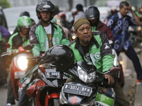 FILE - In this Friday, April 29, 2016, file photo, Go-Jek motorcycle taxi drivers wait for customers in Jakarta, Indonesia. Th Indonesian ride-hailing app Go-Jek says it will expand into Thailand, Vietnam, Singapore and the Philippines in the next few months, vying with rival Grab for Southeast Asian customers.