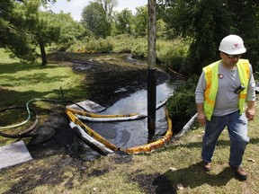 FILE - In this July 29, 2010, file photo, a worker monitors the water in Talmadge Creek in Marshall Township, Mich., near the Kalamazoo River as oil from a ruptured pipeline, owned by Enbridge Inc, is vacuumed out of the water. Enbridge Inc. has agreed to pay a $1.8 million penalty to the U.S. government, which accused the Canadian oil transport company of missing deadlines for inspecting some of its pipelines as required under an earlier settlement following the massive oil spill in southern Michigan.
