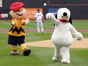 Snoopy, right, throws out the ceremonial first pitch while Charlie Brown looks on prior to the New York Mets playing the Houston Astros in a baseball game at Citi Field in New York on Oct. 3, 2009. DHX Media Ltd. says the sale of nearly half of its stake in the Peanuts entertainment business to a Sony Corp. division for $237 million cash will help reduce the Canadian animation company's debt load and improve its operating results.